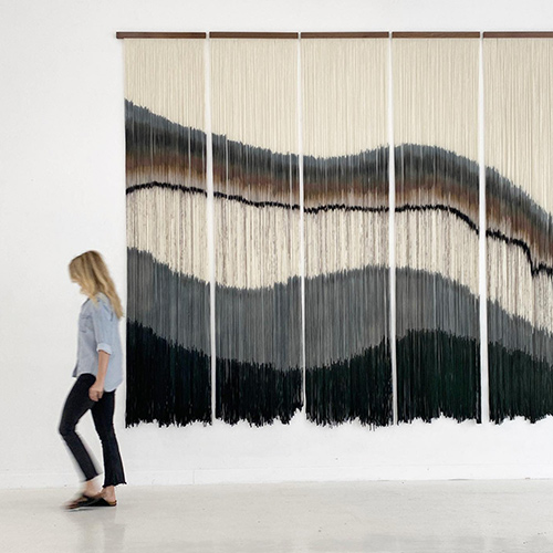 woman next to hanging tapestry
