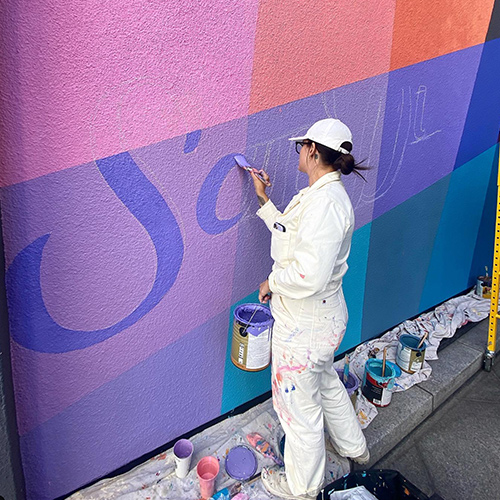 woman painting colorful wall mural