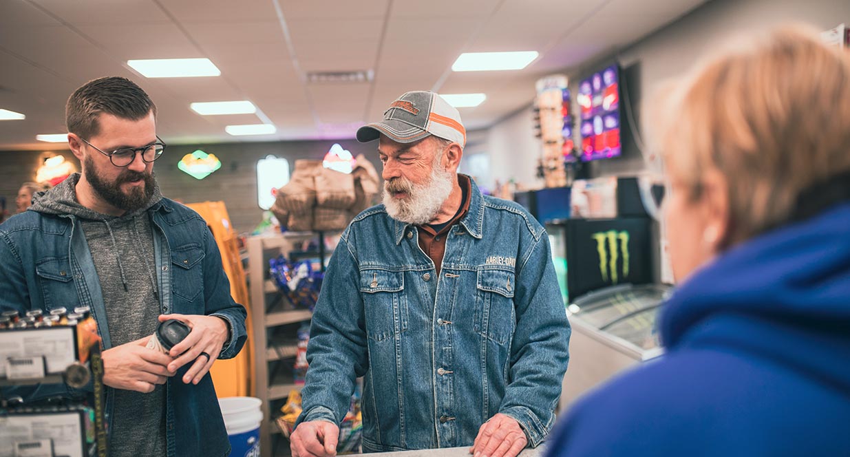 Older man and younger man at counter in convenience store