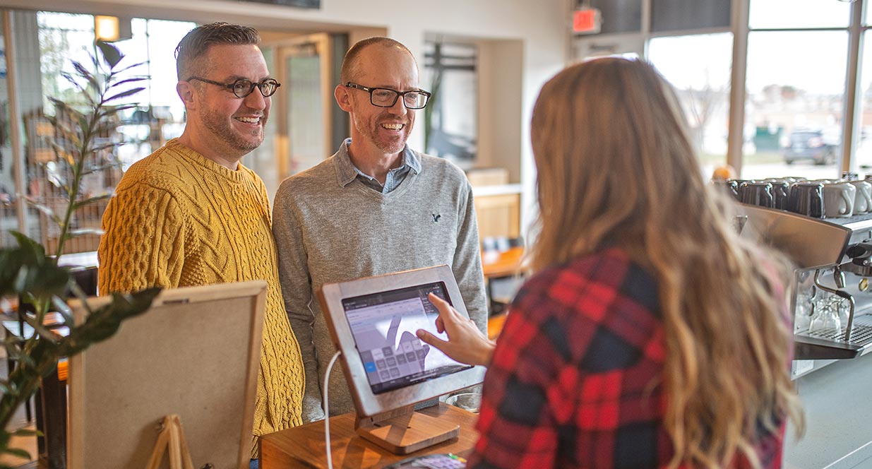 two men ordering at a coffee shop from a girl