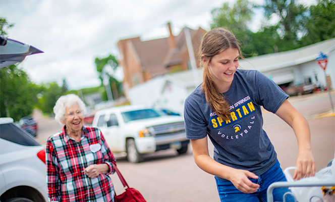 Young woman helping an elderly woman load groceries