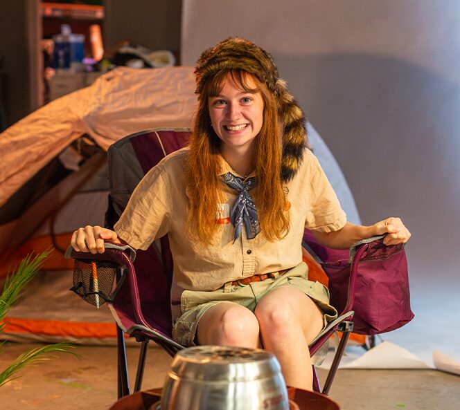 girl in camping outfit sitting